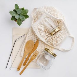 Natural color eco bags, reusable metal and bamboo straws, glass jars, wooden knifes and forks, zero waste cleaning and beauty products, flat lay